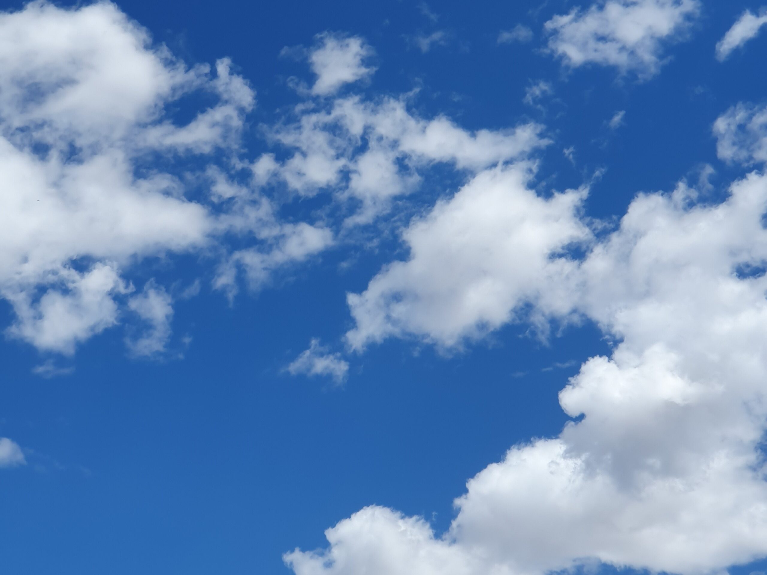 Luchtige wolken die in de heldere blauwe hemel drijven